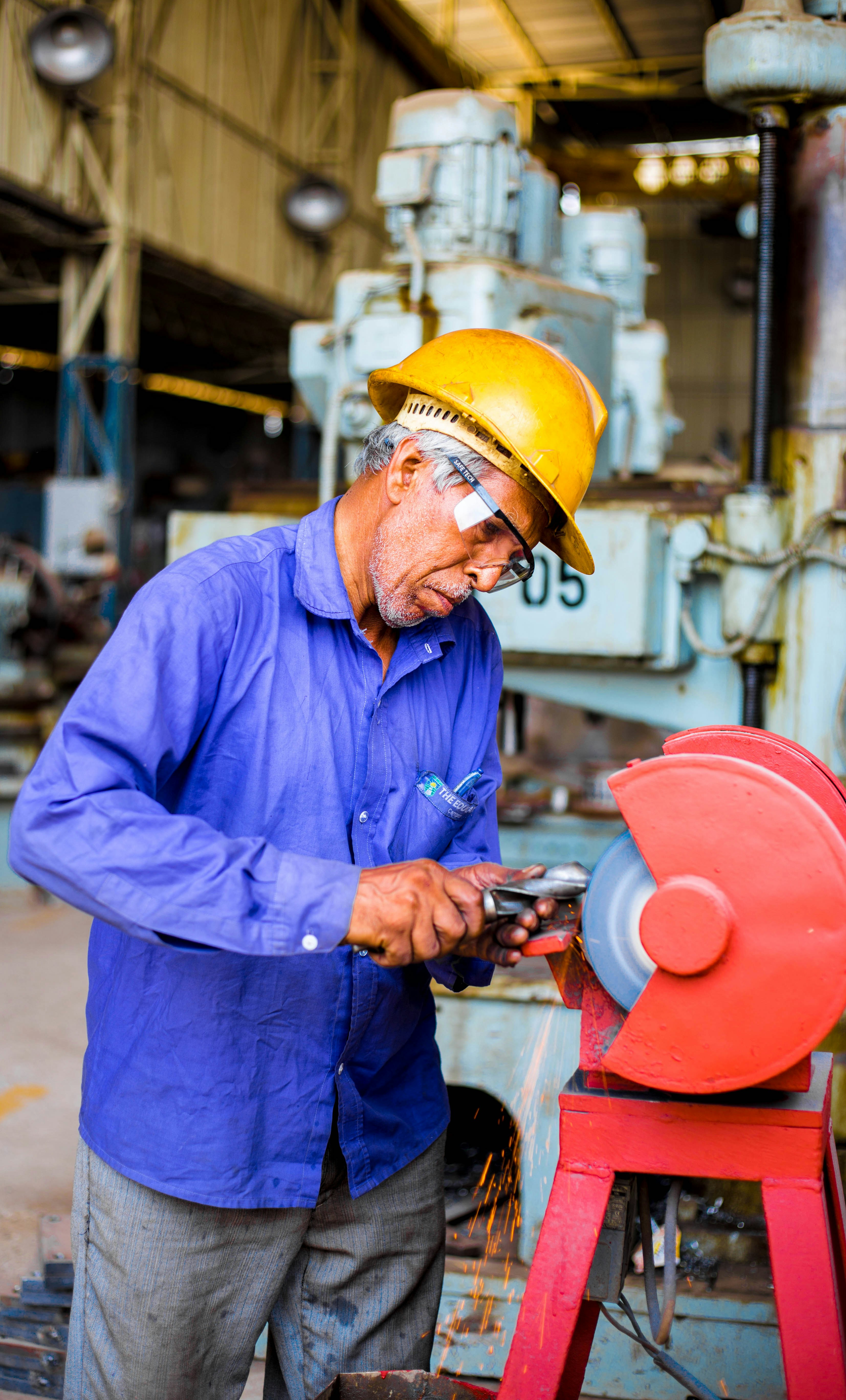 Machinist operating bench grinder on factory floor